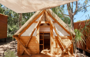 Træhytte Janda Tent ved TAIGA Tarifa i Spanien, med teltlærred og køjesenge, omringet af træer.