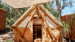 Cabaña de madera Janda Tent en TAIGA Tarifa, España, con techado de lona y naturaleza alrededor.