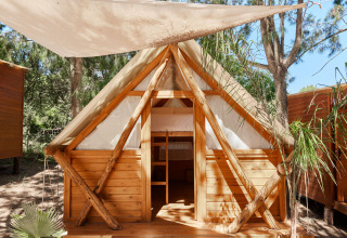 Cabaña de madera Janda Tent en TAIGA Tarifa, España, con techado de lona y naturaleza alrededor.