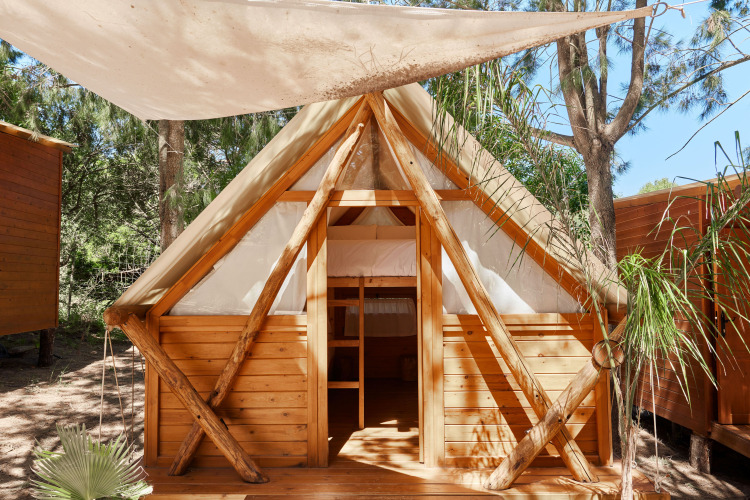 Cabaña de madera Janda Tent en TAIGA Tarifa, España, con techado de lona y naturaleza alrededor.