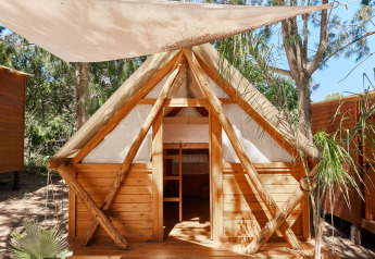 Janda Tent blokhut bij TAIGA Tarifa in Spanje, met stapelbedden en canvas dak, omgeven door bomen.