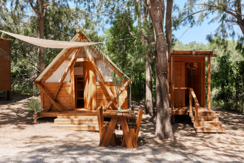 Træhytte kaldet Janda Tent hos TAIGA Tarifa i Spanien, omgivet af træer og udstyret med udendørs bord.