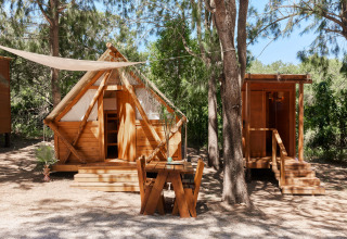 Janda Tent hut bij TAIGA Tarifa in Spanje met houten structuur, omgeven door bomen en natuur.