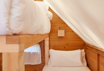 Interieur van de Janda Tent bij TAIGA Tarifa, Spanje, met houten wanden en twee bedden onder een schuin dak.