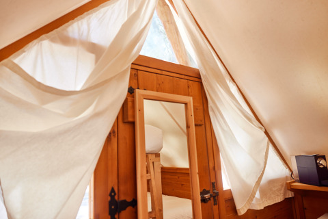 Intérieur de la tente Janda à TAIGA Tarifa, Espagne, avec porte en bois, miroir et rideaux clairs.