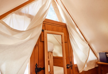 Interno della tenda Janda a TAIGA Tarifa, Spagna, con porta di legno, specchio e tende bianche.