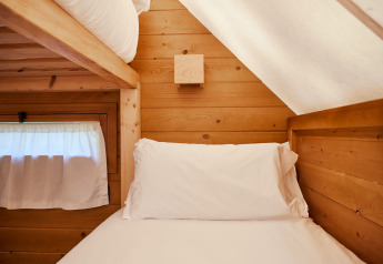 Hyggelig seng med hvidt sengetøj i Janda Tent, en træhytte hos TAIGA Tarifa i Spanien.