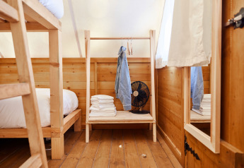 Interno della tenda Janda a TAIGA Tarifa, Spagna: letti a castello in legno, asciugamani, ventilatore.