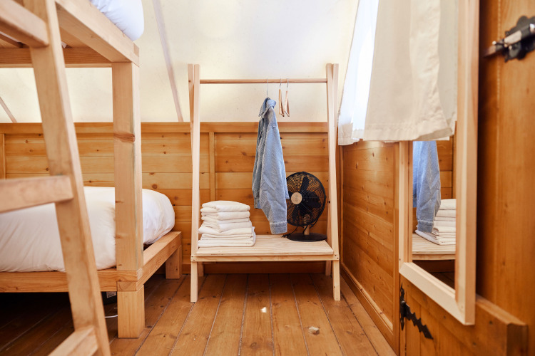 Innenaufnahme des Janda-Zelts bei TAIGA Tarifa, Spanien: Holzmöbel, Etagenbett, Regal mit Ventilator.