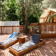 Outdoor deck with sun loungers and a luxury glamping tent at La Cala, TAIGA Tarifa, surrounded by greenery.