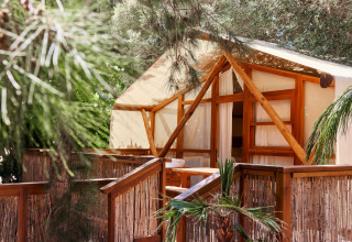 Glamping Luxury Tent La Cala at TAIGA Tarifa, Spain, featuring a wooden terrace surrounded by lush greenery.