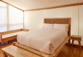 Schlafzimmer im Glamping Luxury Tent La Cala bei TAIGA Tarifa, Spanien, mit Holzbetten und weißen Laken.