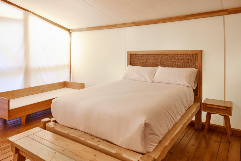 Dormitorio en Glamping Luxury Tent La Cala en TAIGA Tarifa, España, con muebles de madera y cama cómoda.