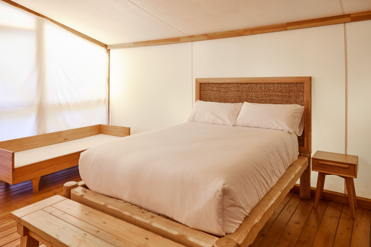Dormitorio en Glamping Luxury Tent La Cala en TAIGA Tarifa, España, con muebles de madera y cama cómoda.