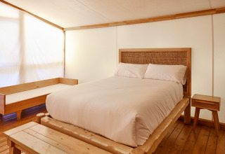 Dormitorio en Glamping Luxury Tent La Cala en TAIGA Tarifa, España, con muebles de madera y cama cómoda.