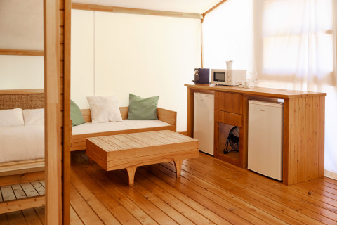 Luksustelt Glamping La Cala på TAIGA Tarifa i Spanien med træinteriør, sofa, bord og tekøkken.