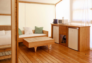 Luksustelt Glamping La Cala på TAIGA Tarifa i Spanien med træinteriør, sofa, bord og tekøkken.
