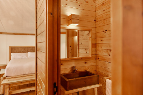 Interno della Glamping Luxury Tent La Cala presso TAIGA Tarifa in Spagna, con pareti in legno e letto.