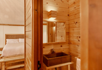 Interior de la tienda Glamping Luxury Tent La Cala en TAIGA Tarifa, España, con paredes de madera y cama.