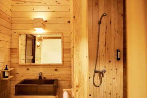 Lyst badeværelse i træ med brusekabine og vask på Glamping Luxury Tent La Cala, TAIGA Tarifa, Spanien.