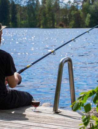 Hombre pescando en un muelle junto al lago en un parque vacacional con alojamiento glamping.