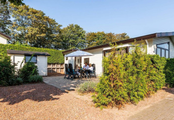 Udendørs foto af feriehytte på EuroParcs Noordwijkse Duinen i Holland med familie, have og solrigt vejr.