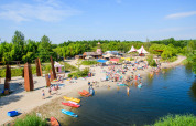 Scena di spiaggia al Netl Camping Kallumaan a Flevoland, Paesi Bassi, con kayak e famiglie che si divertono.