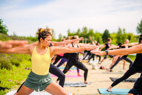 Mujeres practicando yoga al aire libre en Netl Camping Kallumaan, un parque vacacional en Flevoland, Países Bajos.
