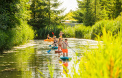 Gezinnen suppen en kajakken door het groene water bij Netl Camping Kallumaan in Flevoland, Nederland.