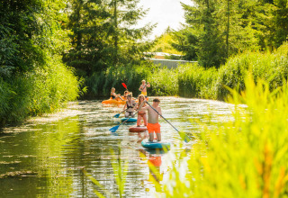 Des gens font du kayak et du paddle sur l'eau à Netl Camping Kallumaan, au cœur de la nature néerlandaise.