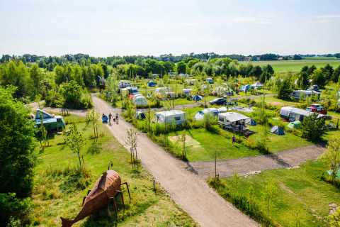 Luchtzicht op Netl Camping Kallumaan vakantiepark in Flevoland, Nederland, met tenten en caravans tussen groen.