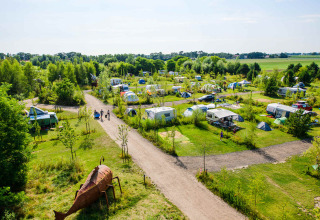 Luchtzicht op Netl Camping Kallumaan vakantiepark in Flevoland, Nederland, met tenten en caravans tussen groen.