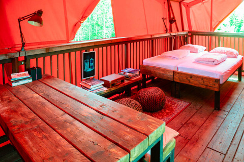 Cozy interior of BoomBoom tree house at Netl Camping Kallumaan, Netherlands with wooden table and bed.
