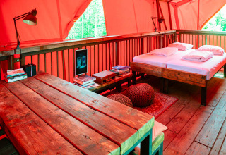 Intérieur chaleureux de la cabane BoomBoom à Netl Camping Kallumaan, table et lit en bois visibles.