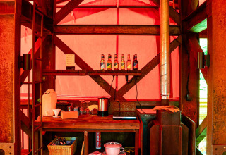 Cuisine rustique et poêle à bois dans la cabane BoomBoom à Netl Camping Kallumaan, Pays-Bas, lumière rouge.