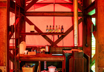 Cocina rústica y estufa de leña en la casa del árbol BoomBoom en Netl Camping Kallumaan, Países Bajos, luz roja.