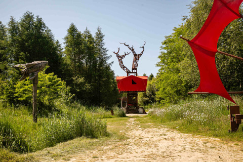 Casa del árbol BoomBoom con detalles rojos rodeada de naturaleza en Netl Camping Kallumaan, Países Bajos.