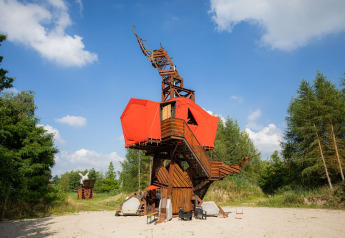 Hébergement de glamping original en bois et toile rouge, situé dans la nature sous un ciel bleu éclatant.