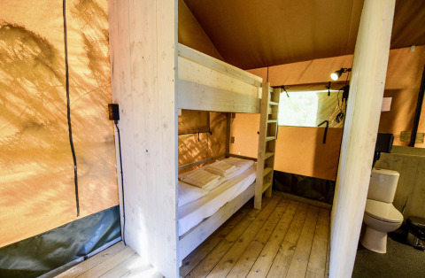 Interior de la tienda safari Lodge + sanitary Leri - UFO en Netl Camping Kallumaan, Países Bajos, con literas y baño.