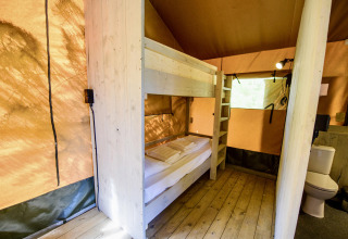 Interior de la tienda safari Lodge + sanitary Leri - UFO en Netl Camping Kallumaan, Países Bajos, con literas y baño.