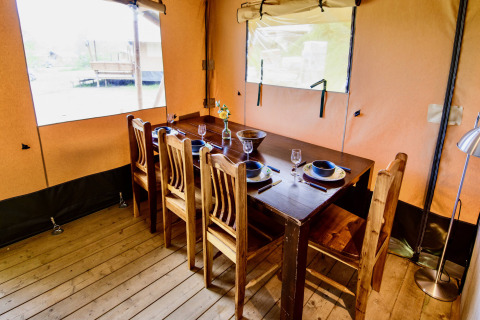 Binnenzicht van een sfeervolle eetruimte in de safaritent Lodge + sanitary Leri - UFO bij Netl Camping Kallumaan.