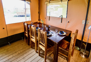 Interior view of a cozy dining area inside the safari tent Lodge + sanitary Leri - UFO at Netl Camping Kallumaan.