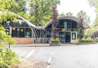 Eingang vom Ferienpark Veluwepark de Bosgraaf in Gelderland, Niederlande, mit Fahrrädern und Natur.
