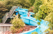 Des familles profitent d’un toboggan bleu entouré de verdure à Veluwepark de Bosgraaf, en Gueldre.