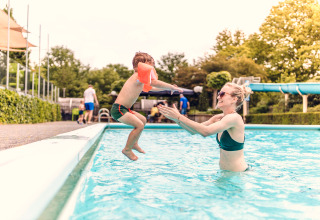 Enfant sautant dans la piscine vers un adulte au parc de vacances Veluwepark de Bosgraaf, Gelderland, Pays-Bas.