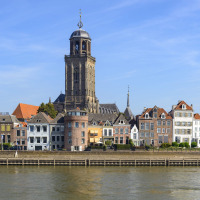 Vista al otro lado del río hacia edificios históricos y una torre de iglesia cerca de Lieren, Gelderland, Holanda.