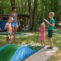 Kinder und Erwachsene spielen Minigolf im Ferienpark de Wrange in Gelderland, Niederlande.
