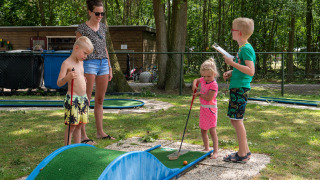 Kinder und Erwachsene spielen Minigolf im Ferienpark de Wrange in Gelderland, Niederlande.
