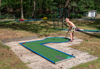 Junge spielt Minigolf auf einer Außenanlage im Recreatiepark de Wrange, Gelderland, Niederlande.