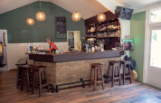 Bar intérieur convivial au Recreatiepark de Wrange en Gueldre, Pays-Bas, avec tabourets en bois et serveuse.